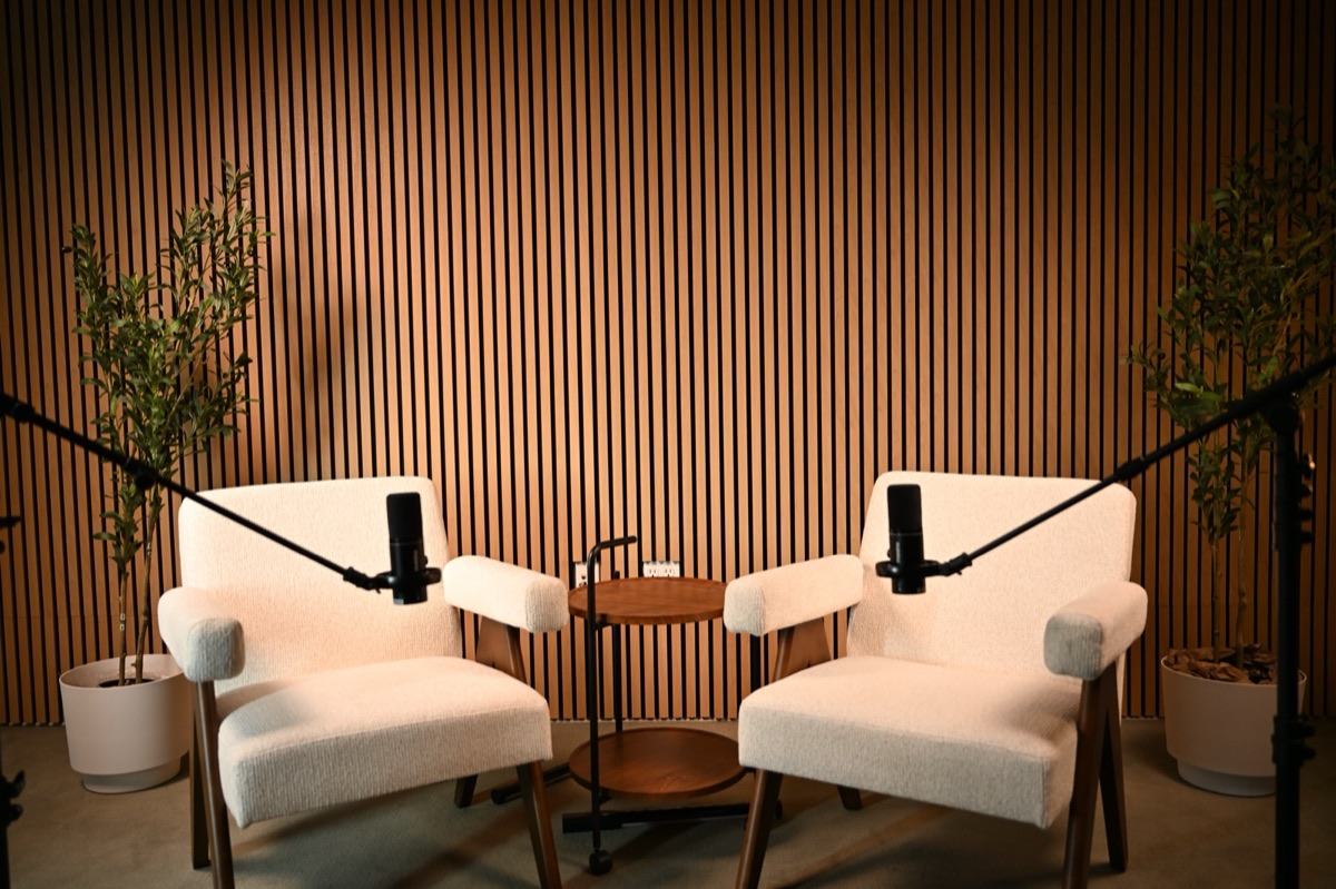 The Axeom studio in Addison, TX &mdash; wood-slat backdrop, mic booms, and cinema lighting.